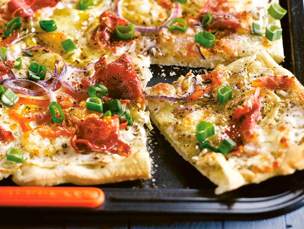 Pizza mit Parmaschinken, Ricotta, Tomaten, Zwiebeln und Mozzarella